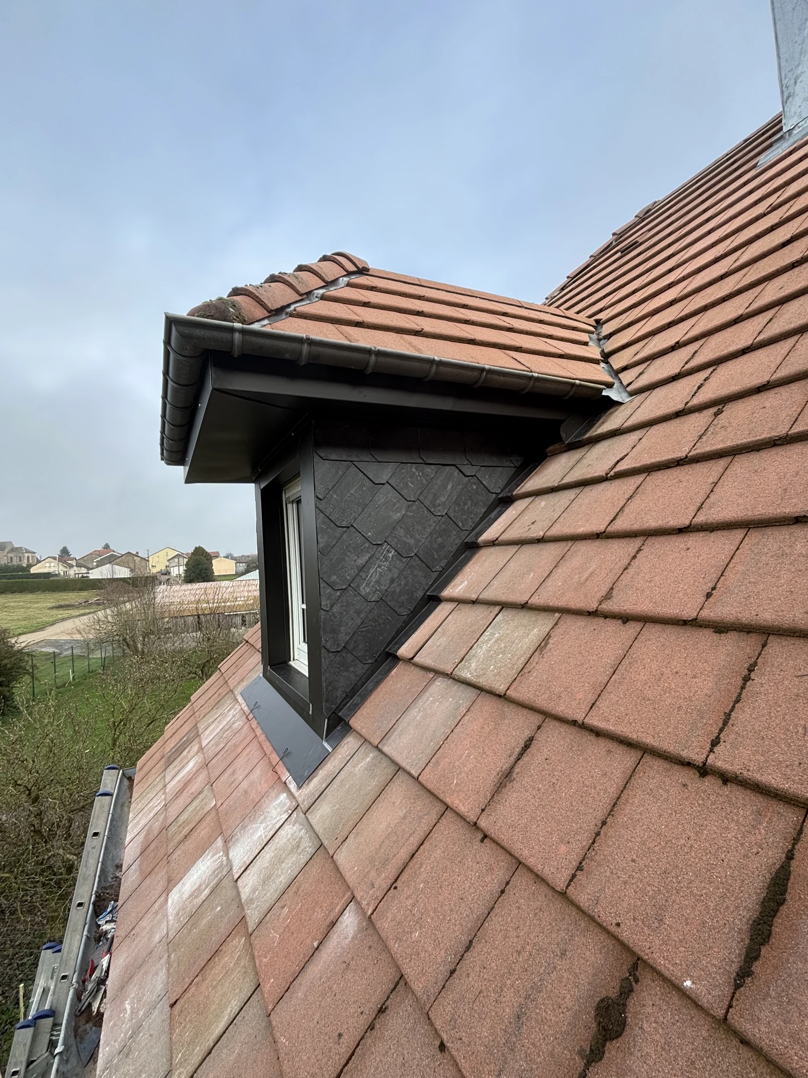 Une personne nettoie une surface vitrée avec un racloir professionnel, créant des traces de mousse savonneuse bleue et blanche sur la vitre