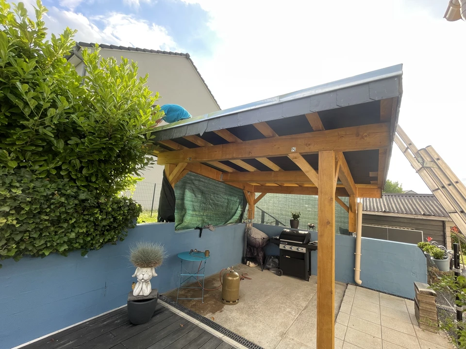 Chantier de construction en extérieur avec ouvrier en tenue bleue manipulant des pièces de charpente